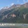 A group of people kayak by a forested mountain range